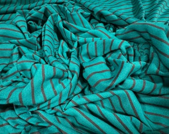 Puede incluir: Tela rayada de color turquesa y negro con un tacto suave y texturado. La tela está arrugada y doblada, mostrando la textura y el drapeado.