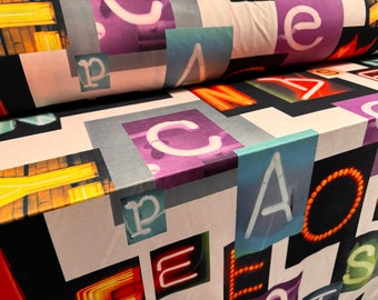 May include: Fabric with a neon sign pattern featuring letters of the alphabet in various colors and styles. The letters are arranged in a random pattern on a white background.