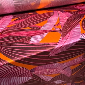 May include: Orange fabric with a pink and burgundy leaf pattern. The fabric is folded in half, showing the pattern on both sides.