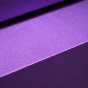 Pu&ograve; includere: Primo piano di due pezzi di tessuto viola piegati uno sopra l'altro. Il tessuto ha una consistenza morbida e soffice.