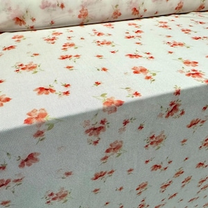 May include: White fabric with a small-scale floral print in shades of orange and green.