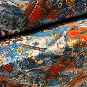 May include: Blue fabric with a repeating pattern of denim, zippers, and other hardware. The fabric has a distressed look and is perfect for crafting projects.
