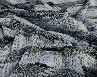 May include: Close-up of a black and white knitted fabric with a textured pattern. The fabric is soft and has a slightly fuzzy texture.