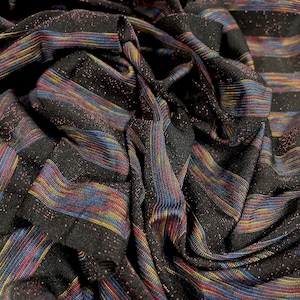 May include: Black fabric with colourful stripes. The fabric has a shimmery, glittery texture.