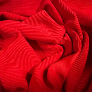Peut inclure: Gros plan sur un tissu côtelé rouge, montrant la texture et les plis du matériau.