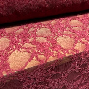 May include: Burgundy lace fabric with a delicate floral pattern. The lace has a subtle shimmer and is perfect for adding a touch of elegance to any project.