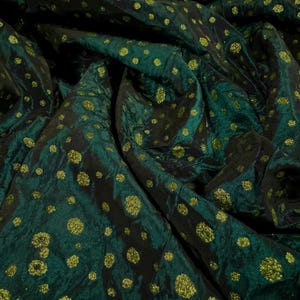 May include: Green fabric with gold glitter polka dots. The fabric is crumpled and has a sheen.