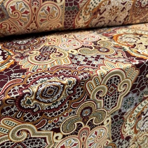May include: A close-up of a fabric with a paisley pattern in shades of burgundy, gold, cream, and green.
