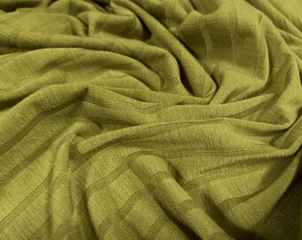 May include: Close-up of a textured, olive green fabric with a ribbed pattern. The fabric is soft and drapes nicely.