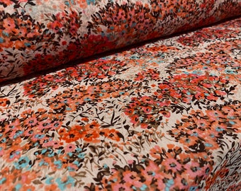 May include: A close-up of a fabric with a floral pattern. The fabric is white with a brown, pink, and blue floral design. The fabric is folded in half.