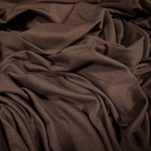 May include: A close-up of a brown fabric with a soft, wrinkled texture. The fabric is smooth and appears to be made of a lightweight material.