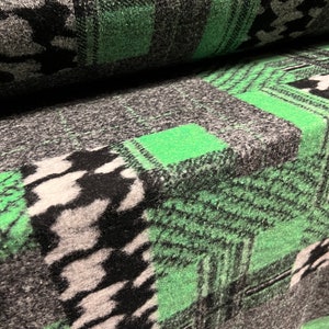 May include: Close-up of a green and black patterned fabric with a fuzzy texture. The fabric is folded over, showing the pattern on both sides.