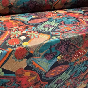 Puede incluir: Tela colorida con un patr&oacute;n repetido de setas estilizadas, flores y formas abstractas en tonos rojos, naranjas, turquesas y morados. La tela tiene una textura tejida y un fondo oscuro.