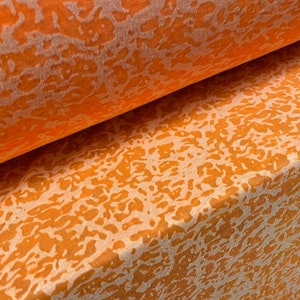 May include: A roll of orange fabric with a white abstract pattern. The fabric has a slightly textured surface.