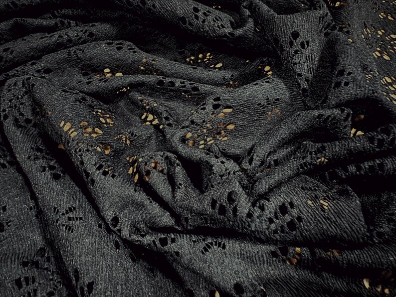 May include: Black lace fabric with a delicate floral pattern. The fabric is soft and has a slightly textured surface.