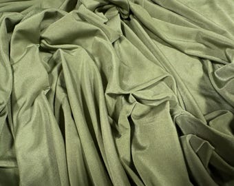 May include: Close-up of olive green fabric with soft folds and a subtle sheen. The material appears to be a lightweight knit or woven textile, suitable for apparel or home decor projects. The fabric is draped, creating shadows and texture.