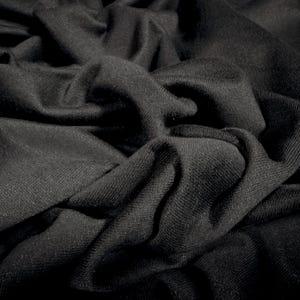 May include: Close-up of black fabric with visible texture and folds. The fabric appears soft and drapes in a natural, flowing manner. The dark color and texture suggest a material suitable for clothing or home decor.