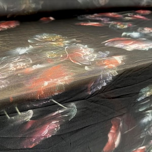 Könnte beinhalten: Nahaufnahme eines schwarzen Stoffes mit floralem Muster. Das Design zeigt große, detaillierte Blumen in Rot-, Rosa- und Weißtönen vor einem dunklen Hintergrund. Der Stoff wirkt weich und fließend, geeignet für Kleidung oder Heimdekoration.