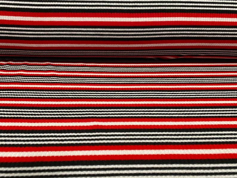 May include: Red, black, and white striped fabric with a ribbed texture. The fabric is woven with horizontal stripes.