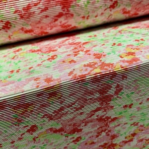 May include: A close-up of a white fabric with a pink and green floral pattern. The fabric has a crinkled texture and is folded in half.