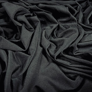 May include: Black fabric with a smooth, silky texture. The fabric is draped and folded, creating a soft, flowing look.