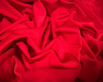 May include: A close-up of a smooth, red fabric with soft folds and wrinkles. The fabric is a deep, rich red color.