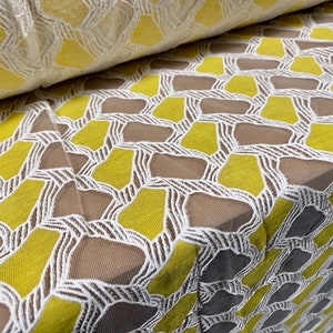 May include: Yellow and white geometric patterned lace fabric. The fabric has a mesh-like texture with a repeating pattern of yellow diamonds and white lines.
