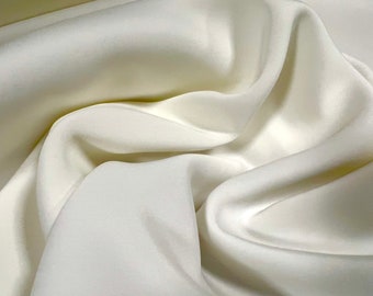 Puede incluir: Primer plano de una tela blanca lisa con pliegues y arrugas suaves. La tela es sedosa y lujosa, con un brillo sutil.
