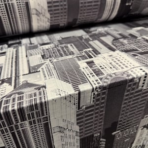 May include: Black and white fabric with a repeating pattern of city buildings. The fabric has a textured surface and a subtle sheen.