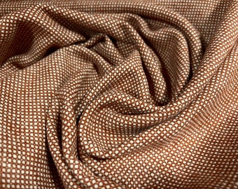 May include: Brown fabric with a white polka dot pattern. The fabric is folded and textured.