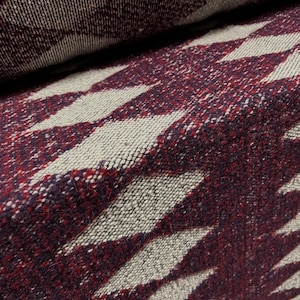 May include: Close-up of a burgundy and cream woven fabric with a diamond pattern. The fabric is soft and textured, with a subtle sheen.