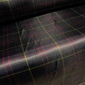 May include: Black fabric with a plaid pattern in pink and yellow.