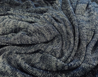 May include: A close-up of a soft, blue and gray knit fabric with a subtle sparkle. The fabric is textured and has a slightly wrinkled appearance.