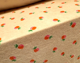 May include: A close-up of a beige fabric with a repeating pattern of pink and orange peaches. The fabric has a slightly textured surface.