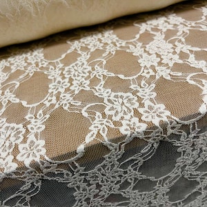 May include: White lace fabric with a floral pattern. The lace is delicate and has a soft, flowing texture.