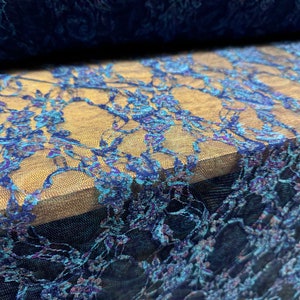 May include: Blue lace fabric with a floral pattern. The lace has a shimmery finish and is delicate and intricate.