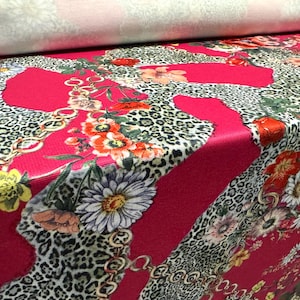 Op de afbeelding: Roze stof met een luipaardprint, bloemenpatroon en gouden kettingontwerp.