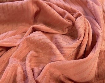 May include: Close-up of a peach-colored ribbed fabric. The fabric is soft and has a subtle texture.