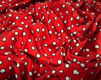 May include: Red fabric with white polka dots. The fabric is wrinkled and has a soft texture.