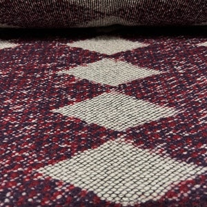 May include: Close-up of a woven fabric with a checkered pattern in shades of burgundy and white.