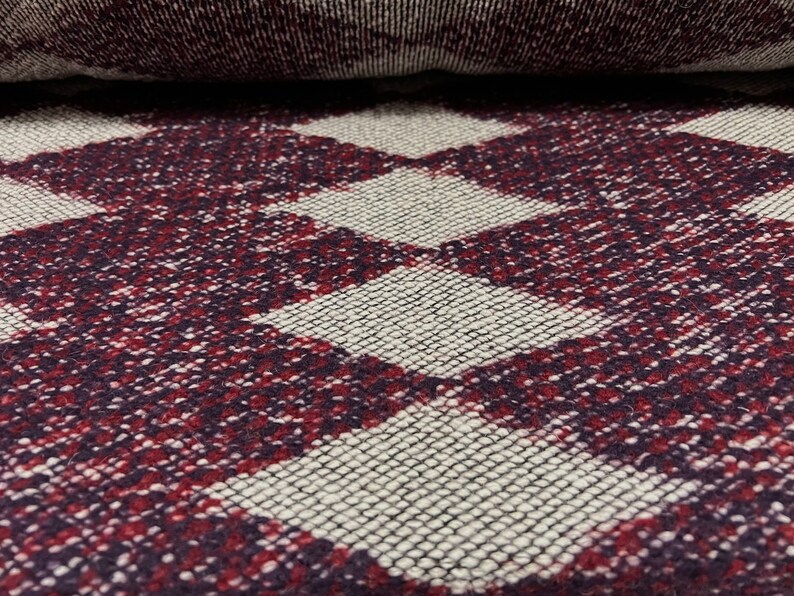 May include: Close-up of a woven fabric with a checkered pattern in shades of burgundy and white.