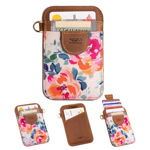 May include: Floral print card holder with brown leather accents. The card holder features a colorful floral pattern with pink, orange, and blue flowers. It has a small metal ring and the brand name "POCKT" is visible.