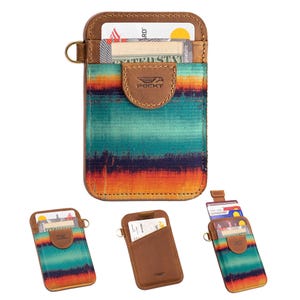 May include: A leather card holder with a colorful striped fabric front. The holder has a brown leather border, a small loop, and a flap with the brand name "POCKT". Several cards are visible inside the holder.