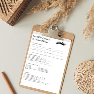 May include: A clipboard holds a white "Lash Client Intake & Consent Form". The form includes sections for personal and medical information, and a history section. A decorative eyelash graphic is present.