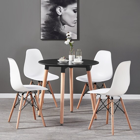 Contemporary dining set with a black and white round table and 4 Eiffel style plastic chairs with wooden legs in a Nordic style