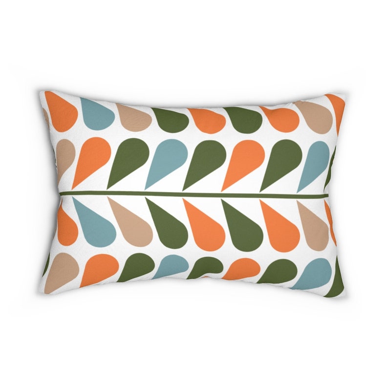 Op de afbeelding: Rechthoekig kussen met een herhalend patroon van druppelvormen in oranje, olijfgroen, beige en blauw op een witte achtergrond. Een groene horizontale lijn verdeelt het patroon.