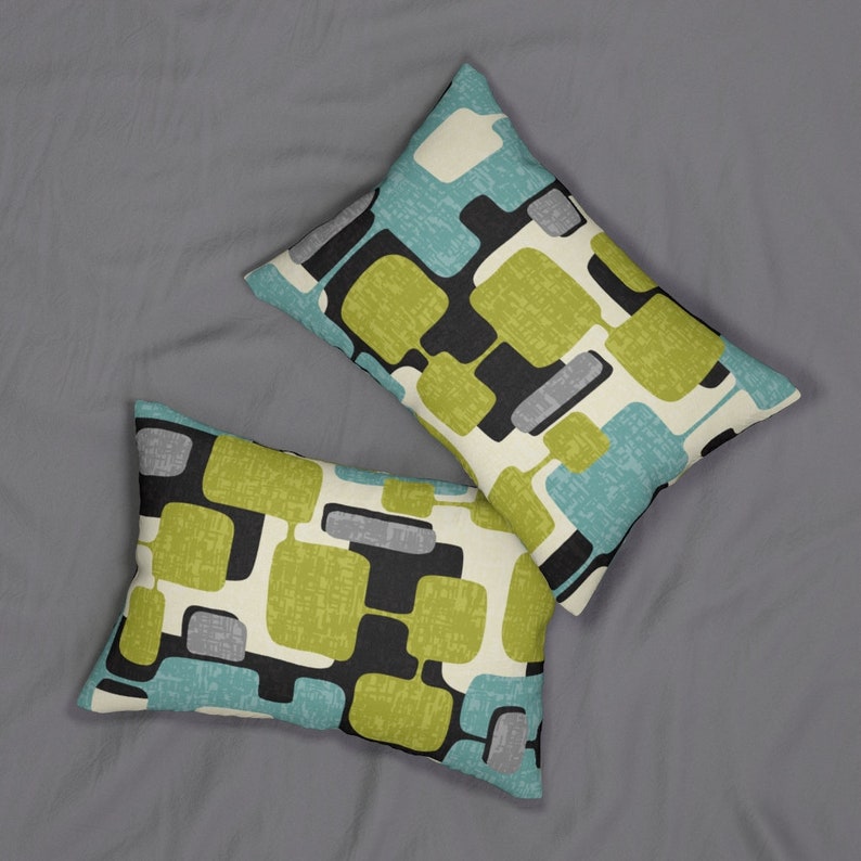 May include: Two decorative throw pillows with a geometric pattern in shades of green, blue, black, and white. The pillows are on a grey surface.