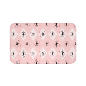 May include: Pink bath mat with a black and white geometric pattern of stars and diamonds.