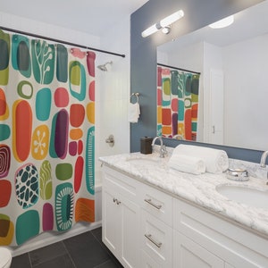 Pode incluir: Um banheiro branco com uma cortina de chuveiro que apresenta um padr&atilde;o abstrato colorido de c&iacute;rculos, ovais e redemoinhos. A cortina de chuveiro &eacute; feita de tecido e tem um fundo branco. O banheiro tamb&eacute;m tem uma pia branca com uma bancada de m&aacute;rmore e duas pias. H&aacute; uma toalha branca na bancada.