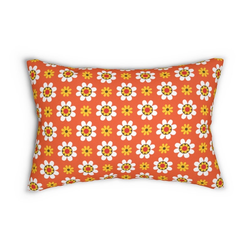 May include: Orange throw pillow with a white and yellow daisy pattern.